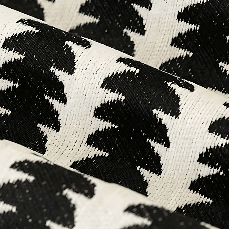 Close-up van de geweven chenille stof in zwart en crème, met het patroon en de dichte textuur van de draden zichtbaar. 2