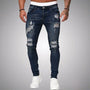 Voorkant van slim fit jeans met scheuren in donkerblauw verweerd denim, gedragen door een model met witte sneakers. 4