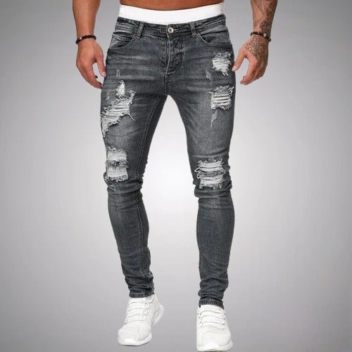 Voorkant van slim fit jeans met scheuren in grijs verweerd denim, gedragen door een model met witte sneakers. 5