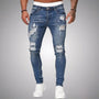 Voorkant van slim fit jeans met scheuren in middenblauw verweerd denim, gedragen door een model met witte sneakers. 3
