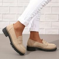Beige loafers met zwarte profielzool gedragen met gescheurde witte jeans, een voet iets opgetild zodat de zijkant zichtbaar is. 3