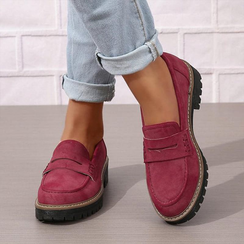 Bordeauxrode loafers met zichtbare stiksels gedragen onder lichtblauwe opgerolde jeans, zijaanzicht van de voeten. 4