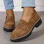 Bruine suèdelook loafers met contrasterende witte stiksels aan een model met lichtblauwe jeans, close-up van de dikke zool. 5