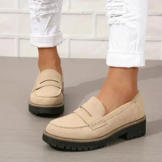 Beige loafers met zwarte zool gedragen onder opgerolde witte jeans, schuin van voren gezien. 7