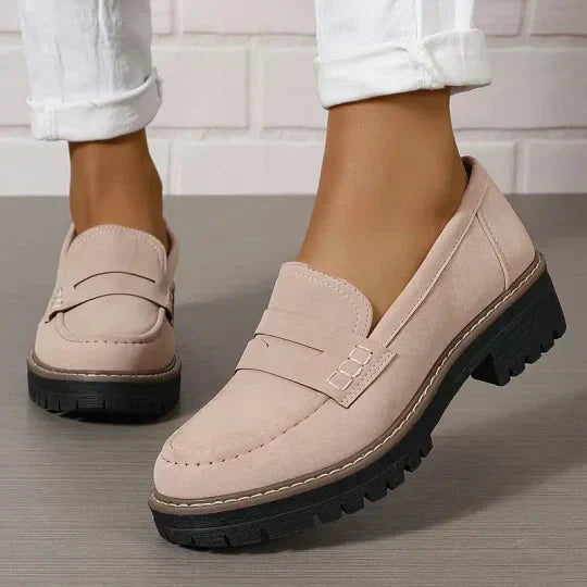 Zachtroze loafers met zwarte profielzool gedragen met opgerolde witte broek, close-up van het bovenwerk. 8