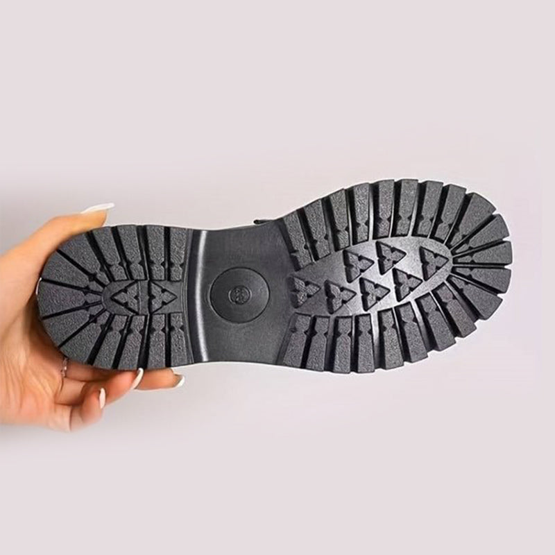 Onderkant van de loafer in een hand: zwarte profielzool met diepe groeven en driehoekig patroon voor extra grip. 10