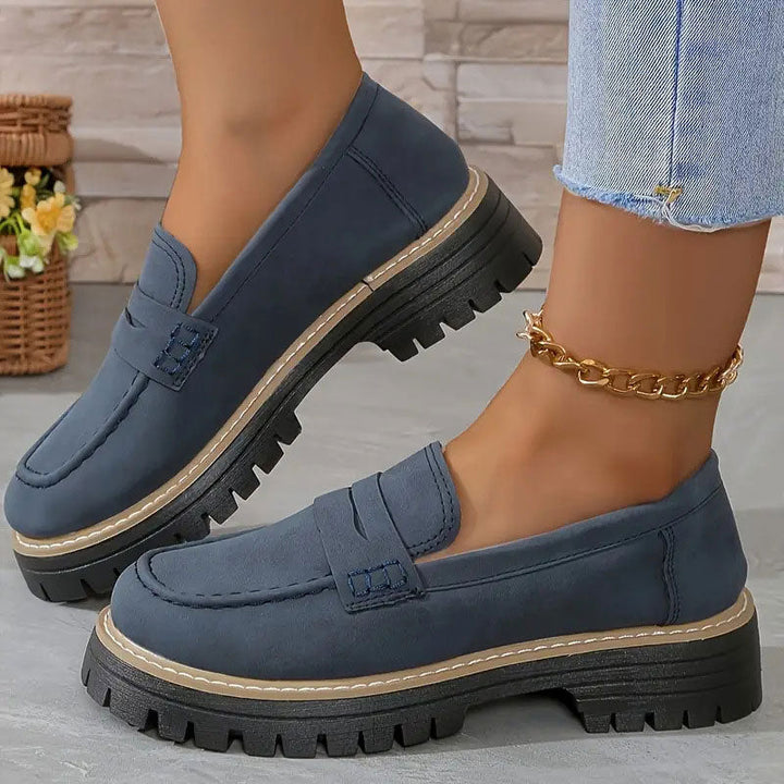 Donkerblauwe suèdelook loafers met dikke zwarte zool, gedragen met gouden enkelbandje en uitgerafelde jeans. 16