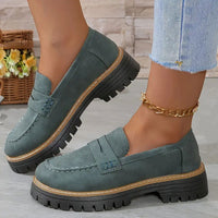 Grijsgroene suèdelook loafers met bruine rand langs de zwarte profielzool, gedragen met gouden enkelbandje en jeans. 15