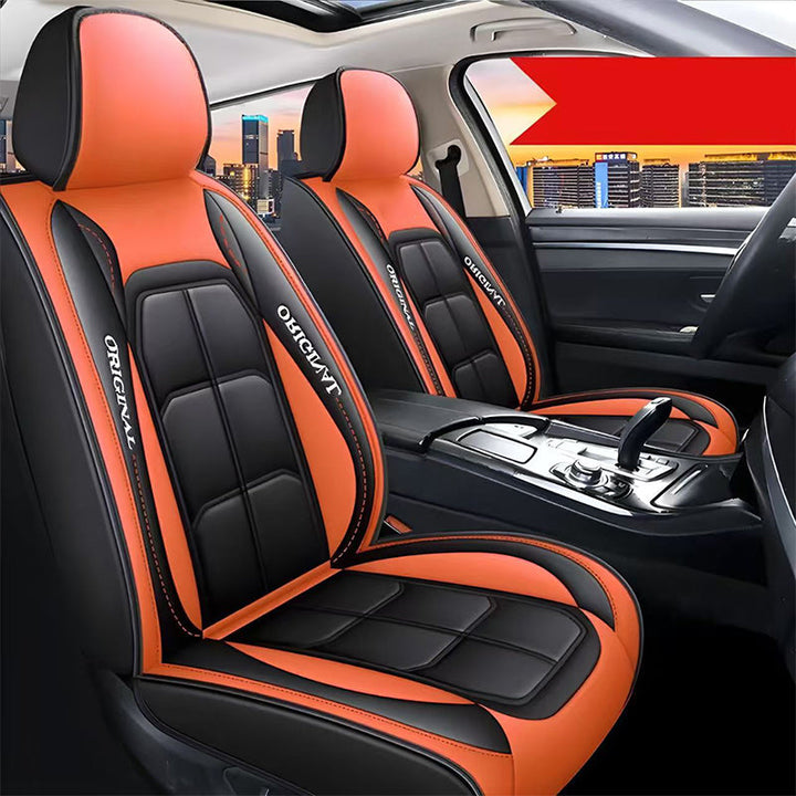 Twee voorstoelen met zwart-oranje leerlook hoezen, oranje hoofdsteunen en oranje zijpanelen, met een rode banner rechtsboven in beeld. 15