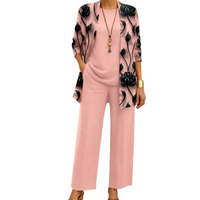 Dezelfde set in roze: cardigan met zwarte bloemenprint, effen shirt en wijde broek, gedragen met lange ketting. 2