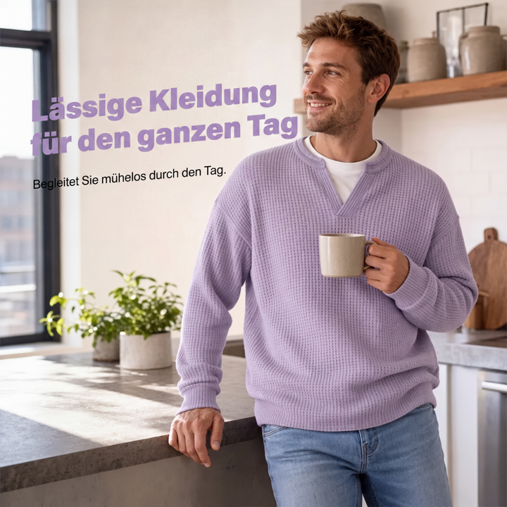 Lachende man in de lila top houdt een kop koffie vast terwijl hij tegen een keukenblad leunt. 5