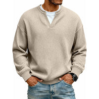 Voorkant van de wafeltop in beige met wit shirt in de V-hals, gedragen met handen in de zakken. 11