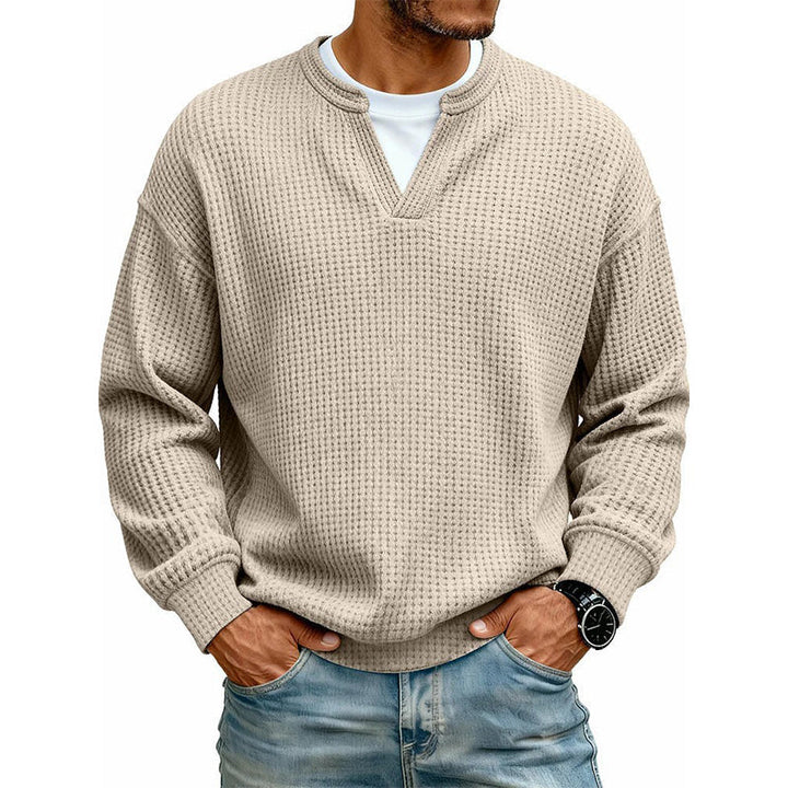 Voorkant van de wafeltop in beige met wit shirt in de V-hals, gedragen met handen in de zakken. 11