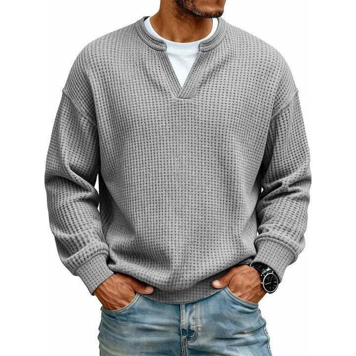Voorkant van de wafeltop in middengrijs met neplaag, gedragen door een model met jeans en horloge. 17