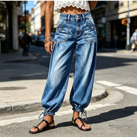 Blauwe barreljeans met hoge taille gedragen op straat, voorkant met twee opgestikte zakken en strikkoorden aan de enkels. 2