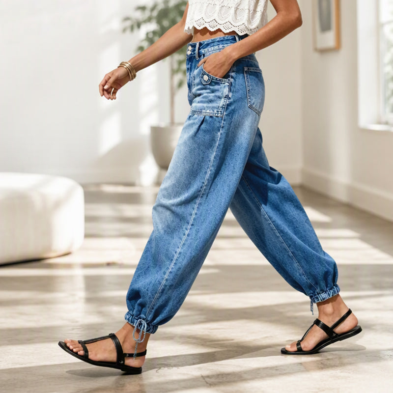 Zijaanzicht van een model dat in de blauwe barreljeans loopt, met zichtbare zijzak, ballonpijpen en gestrikte zoom. 7