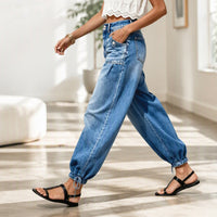 Zijaanzicht van een model dat in de blauwe barreljeans loopt, met zichtbare zijzak, ballonpijpen en gestrikte zoom. 7