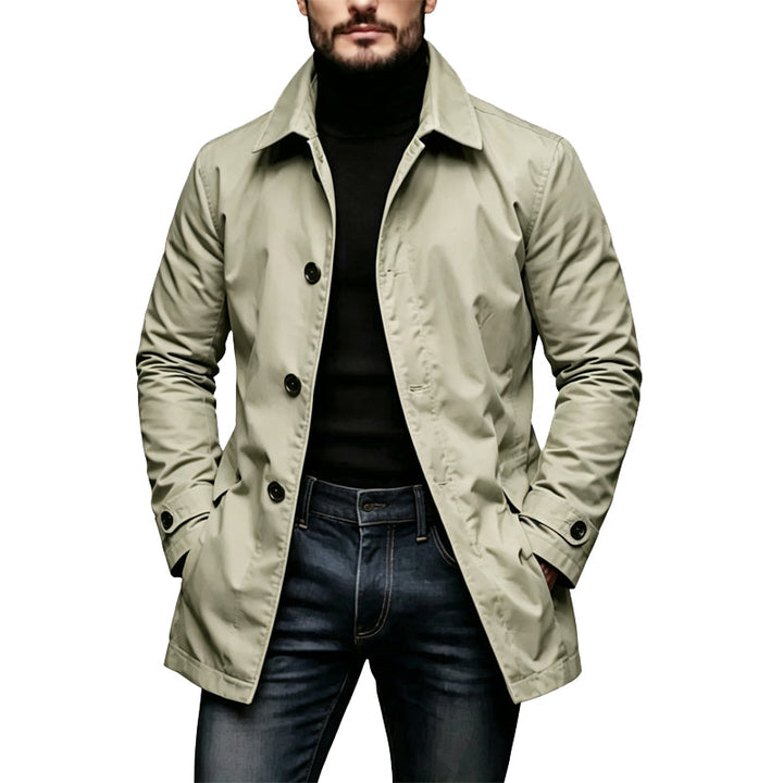 Man draagt de lichte beige-groene versie van de jas met zwarte knopen, gecombineerd met een zwarte coltrui en jeans. 3