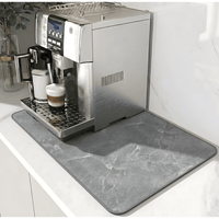 Mat met grijze marmerlook en donkere rand onder een zilverkleurige koffiemachine op een wit aanrechtblad. 12