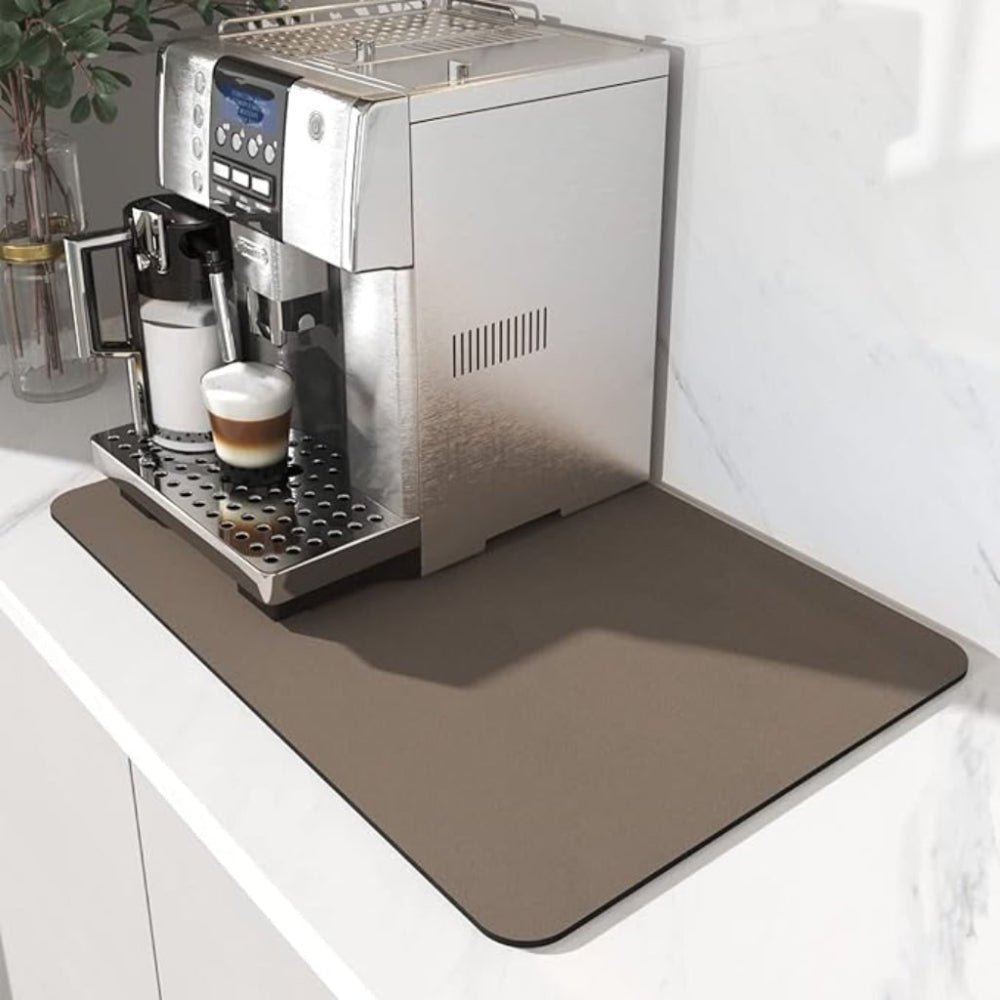 Bruingrijze mat onder een koffiemachine op een wit aanrecht, met een gevuld koffieglas op het druiprooster. 3