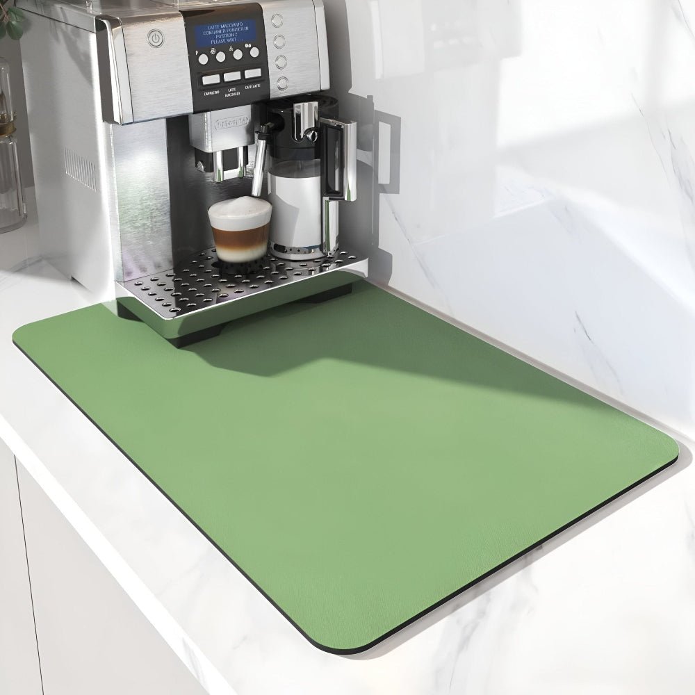 Effen groene mat met afgeronde hoeken onder een koffieapparaat met melkkan en glas, op een wit marmeren aanrecht. 6