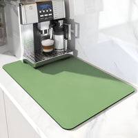 Effen groene mat met afgeronde hoeken onder een koffieapparaat met melkkan en glas, op een wit marmeren aanrecht. 6
