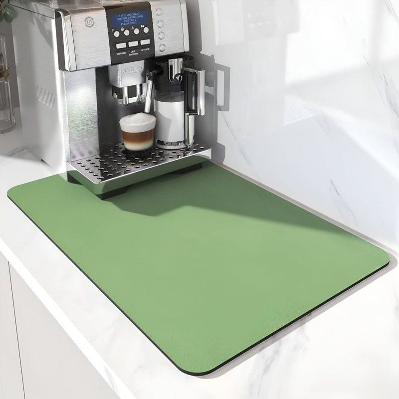 Effen groene mat met afgeronde hoeken onder een koffieapparaat met melkkan en glas, op een wit marmeren aanrecht. 6