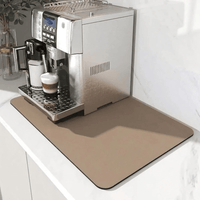 Beige zandkleurige mat onder een zilverkleurige koffiemachine, met schaduwval op het wit marmeren aanrechtblad. 7