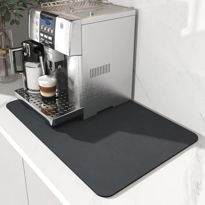 Donkergrijze mat onder een volautomatische koffiemachine op een wit marmeren aanrecht, gezien vanaf de voorzijde. 2