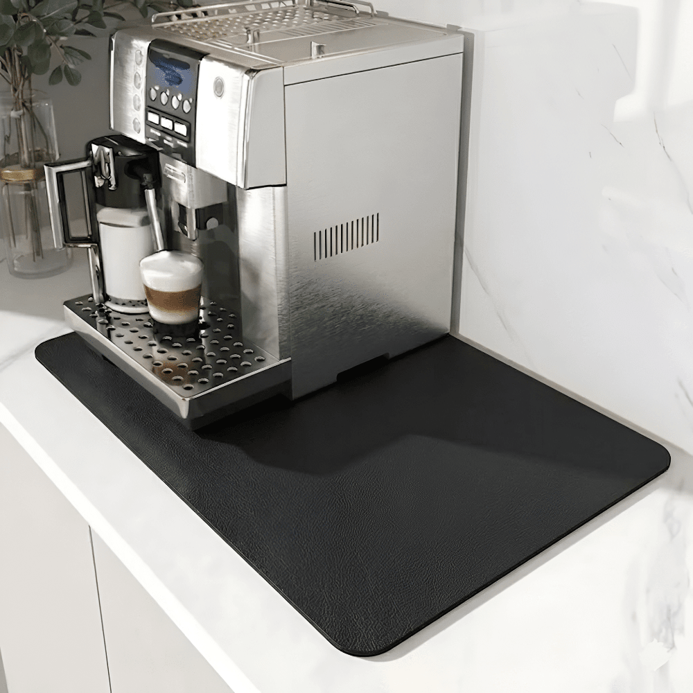 Zwarte mat met fijne leerachtige structuur onder een koffiemachine op een wit marmeren aanrecht. 9