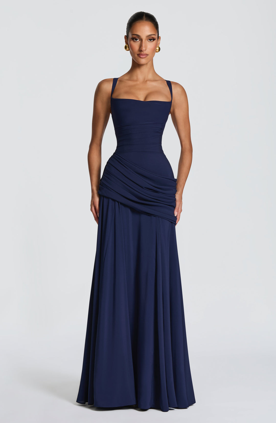 Vooraanzicht van de marineblauwe maxi-jurk op een model, met vierkante halslijn, geplooide taille, heupdrapering en ruim uitlopende rok. 7