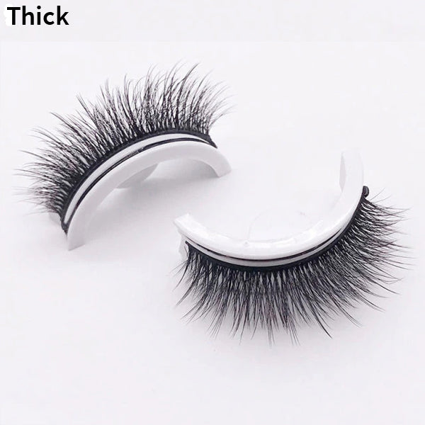 Twee wimperstukjes met dikke, volle donkere wimpers op witte houdertjes, liggend op een lichte achtergrond, de variant dik. 12