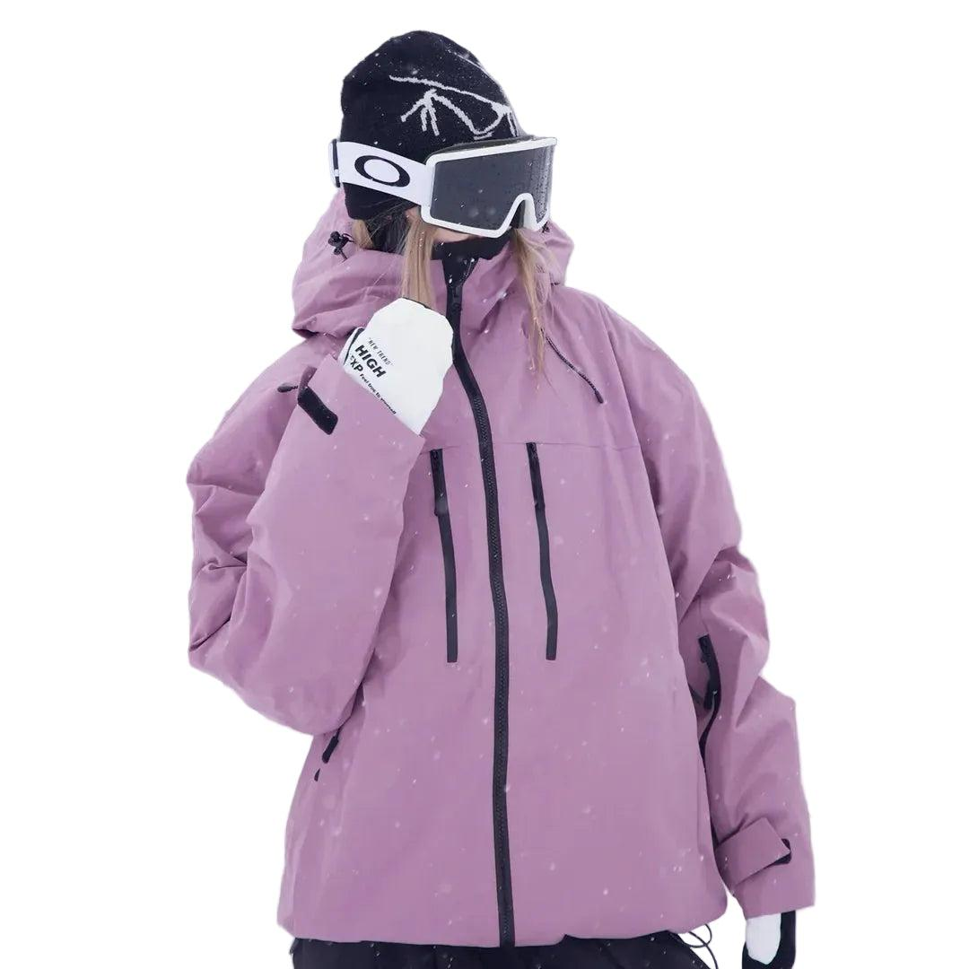 Roze snowjack op een model met muts en skibril, schuin vooraanzicht met zakken met ritssluiting op de borst. 2