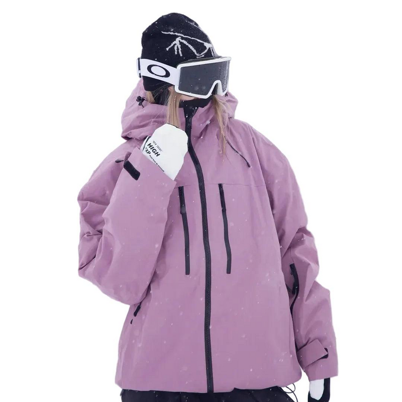Roze snowjack op een model met muts en skibril, schuin vooraanzicht met zakken met ritssluiting op de borst. 2