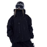 Zwarte snowjack gedragen door een model met muts en skibril, vooraanzicht met hoge kraag en handen in de zakken. 3