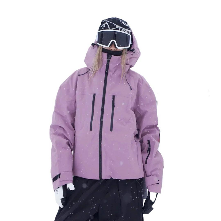 Roze snowjack met capuchon en ritszakken, gedragen door een model in sneeuwval, vooraanzicht met klittenbandmanchetten. 4