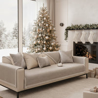 Beige bankhoes met bijpassende kussens op een bank in een kerstversierde woonkamer met boom, open haard en sokken. 2