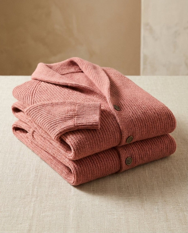 Twee opgevouwen roze geribde vesten op elkaar op een linnen kleed, met sjaalkraag en knopen zichtbaar. 7