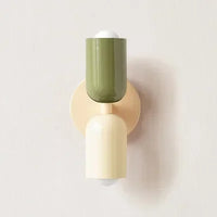 Wandlamp met olijfgroene bovenkap, crème onderkap en crèmekleurige wandplaat, close-up tegen een lichte muur. 18
