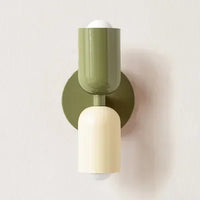 Wandlamp in olijfgroen en crème met olijfgroene ronde wandplaat, close-up tegen een lichte muur. 15