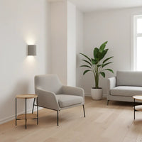 Lichtgrijze wandlamp in een minimalistische woonkamer met fauteuil, bank en grote plant 5