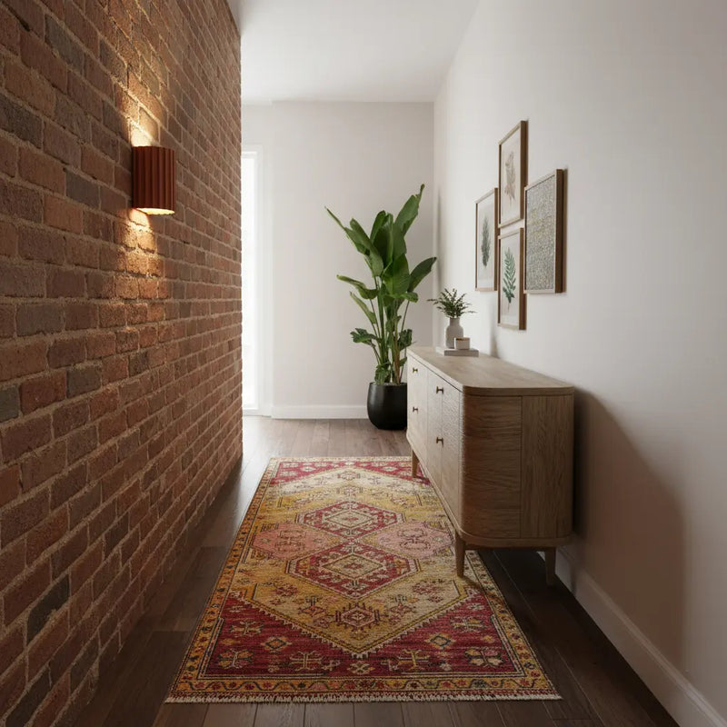 Terracotta wandlamp die een bakstenen muur in een gang met kleed en dressoir verlicht 4