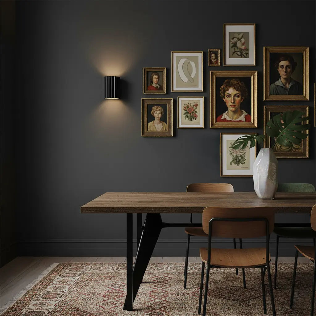 Zwarte geribbelde wandlamp aan een donkere muur boven een houten eettafel met ingelijste portretten 6