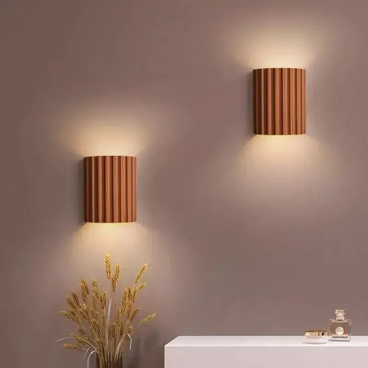 Twee terracotta wandlampen aan een muur, schijnend naar boven en beneden, boven een wit dressoir 8