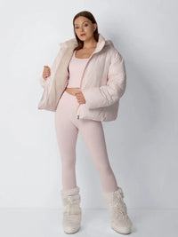 Model in roze pufferjack opent het voorpand om de zachte fleece voering te tonen, met laarzen 8