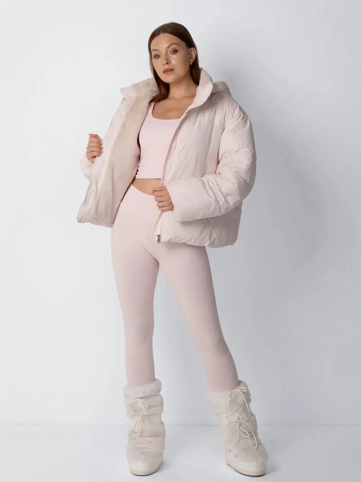 Model in roze pufferjack opent het voorpand om de zachte fleece voering te tonen, met laarzen 8