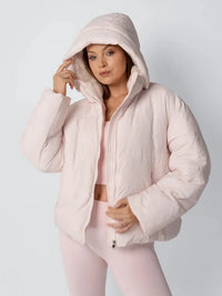 Model in roze pufferjack met capuchon over het hoofd en hand aan de rand van de capuchon 6