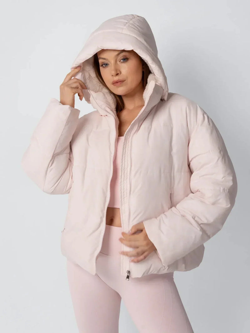 Model in roze pufferjack met capuchon over het hoofd en hand aan de rand van de capuchon 6