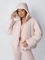 Model in roze pufferjack met capuchon over het hoofd en hand aan de rand van de capuchon 6