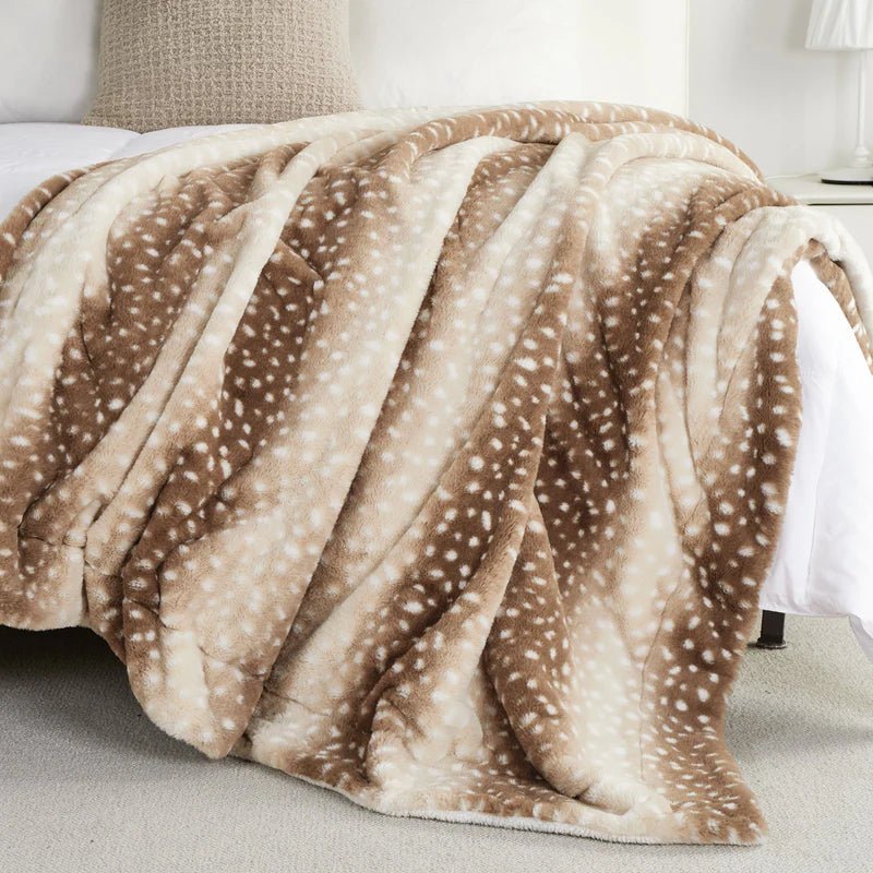 Plaid met hertenstippen losjes over het voeteneinde van een bed gedrapeerd, in warme bruine en crèmekleuren. 3